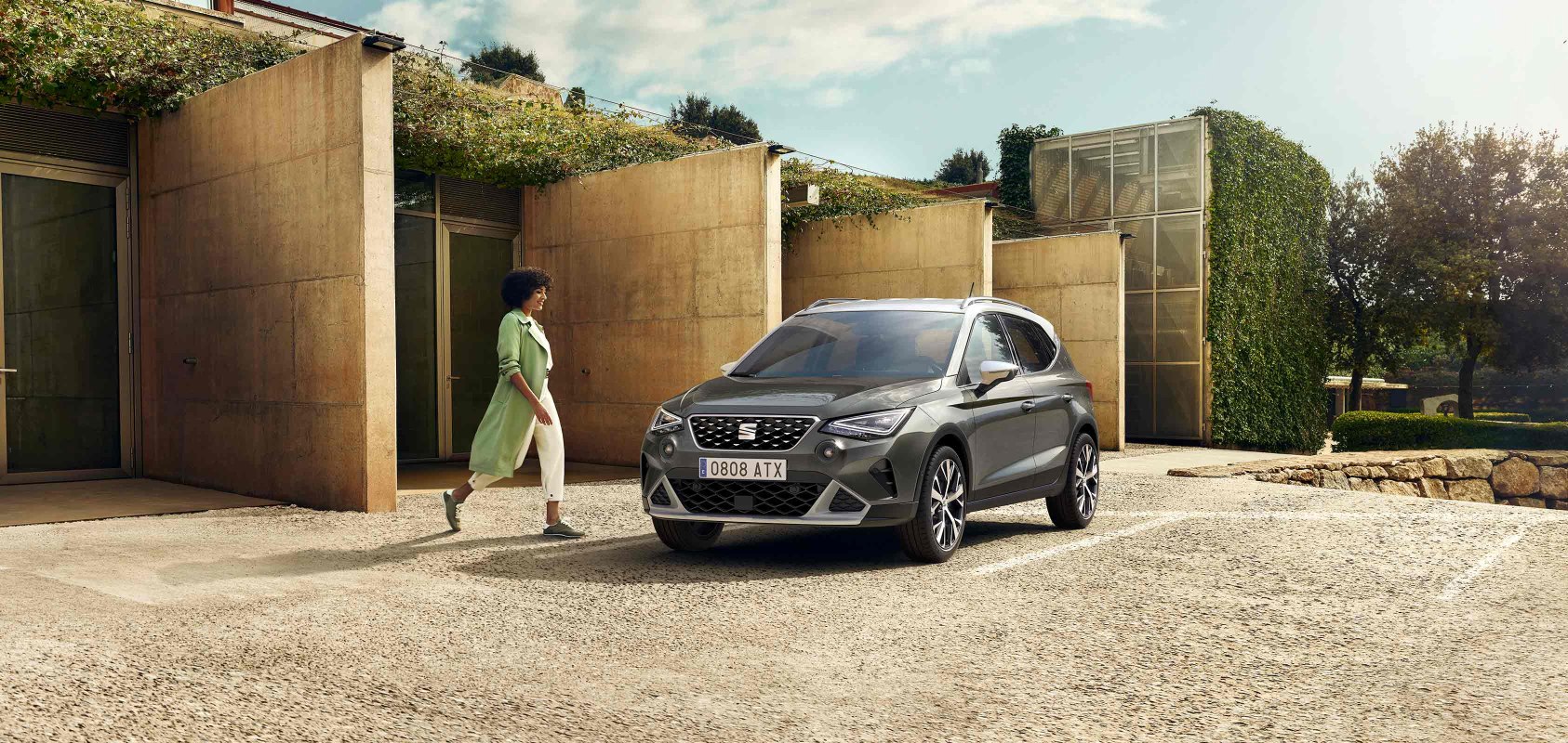Woman walking to SEAT Arona dark camouflage colour with candy white roof