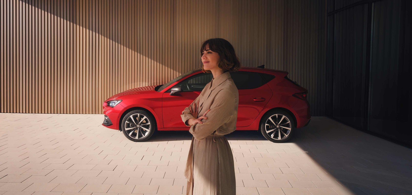 Woman standing close to SEAT Leon 5D desire red colour