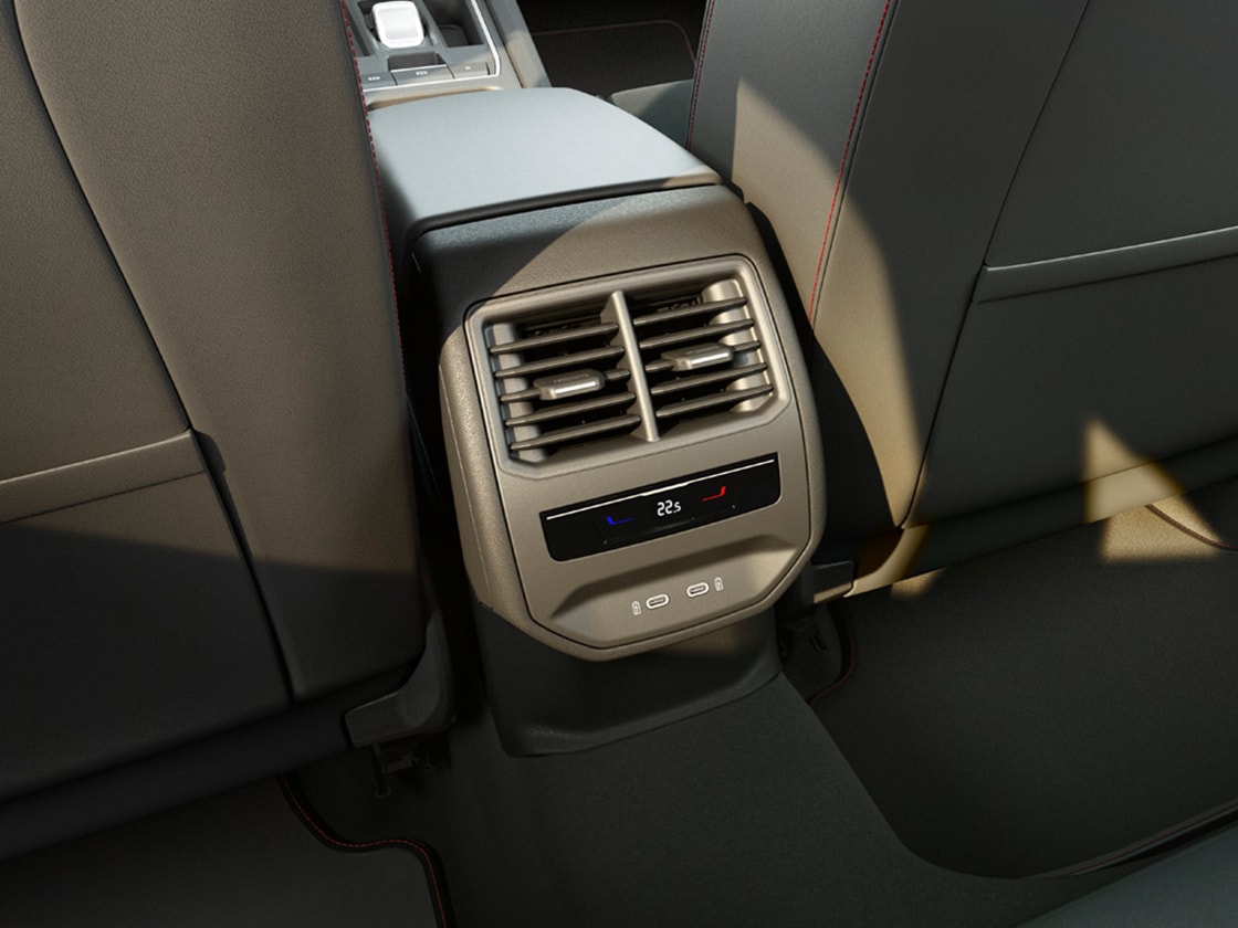 Vista posteriore dell'interno che mostra il Comfort Pack della SEAT Leon con climatizzatore Climatronic a 3 zone, prese USB di tipo C e bracciolo centrale.