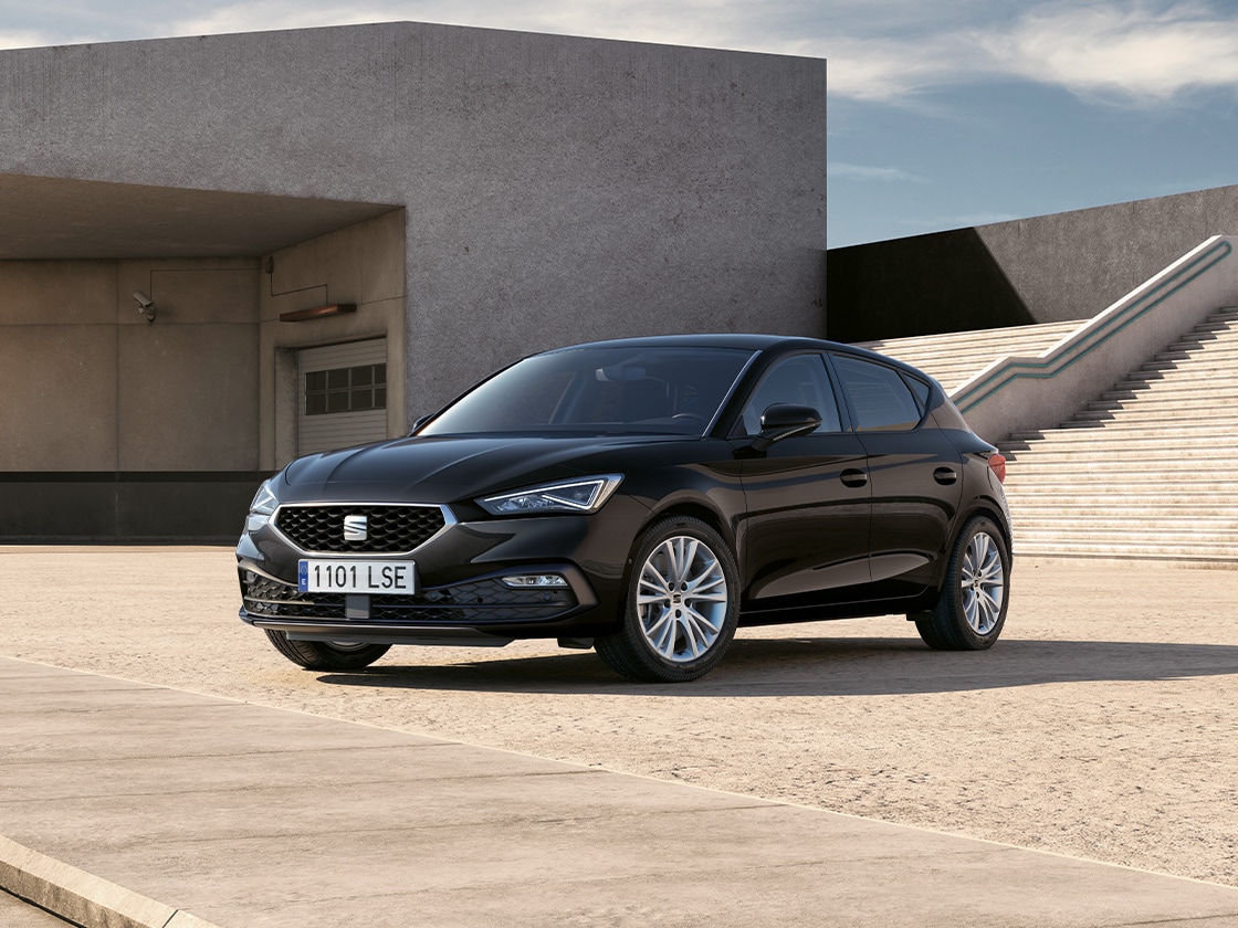 Glossy black mirror covers for the seat leon fr contrasting with the red car body, side view with cement background.