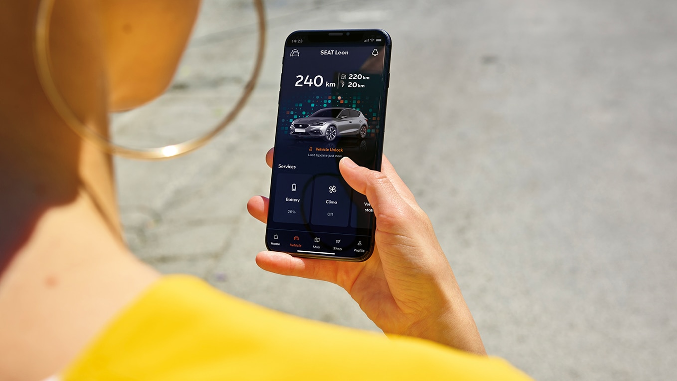 Una persona con in mano uno smartphone mentre utilizza l'App My Seat, una funzionalità di Seat Connect, per l'accesso remoto e le funzionalità del veicolo.