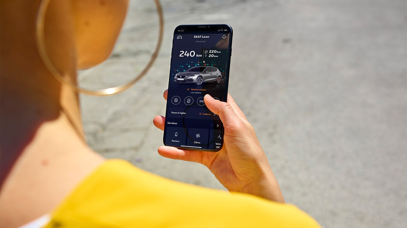 Una persona con in mano uno smartphone mentre utilizza l’App My SEAT, una funzionalità di SEAT Connect, per l’accesso remoto e le funzionalità del veicolo.