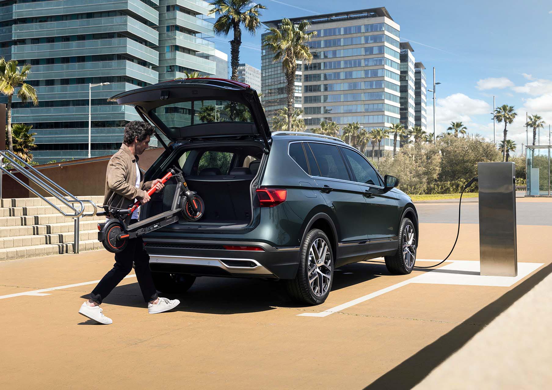 Un uomo carica un SEAT MÓ 65 nel bagagliaio di Nuova SEAT Tarraco XPERIENCE