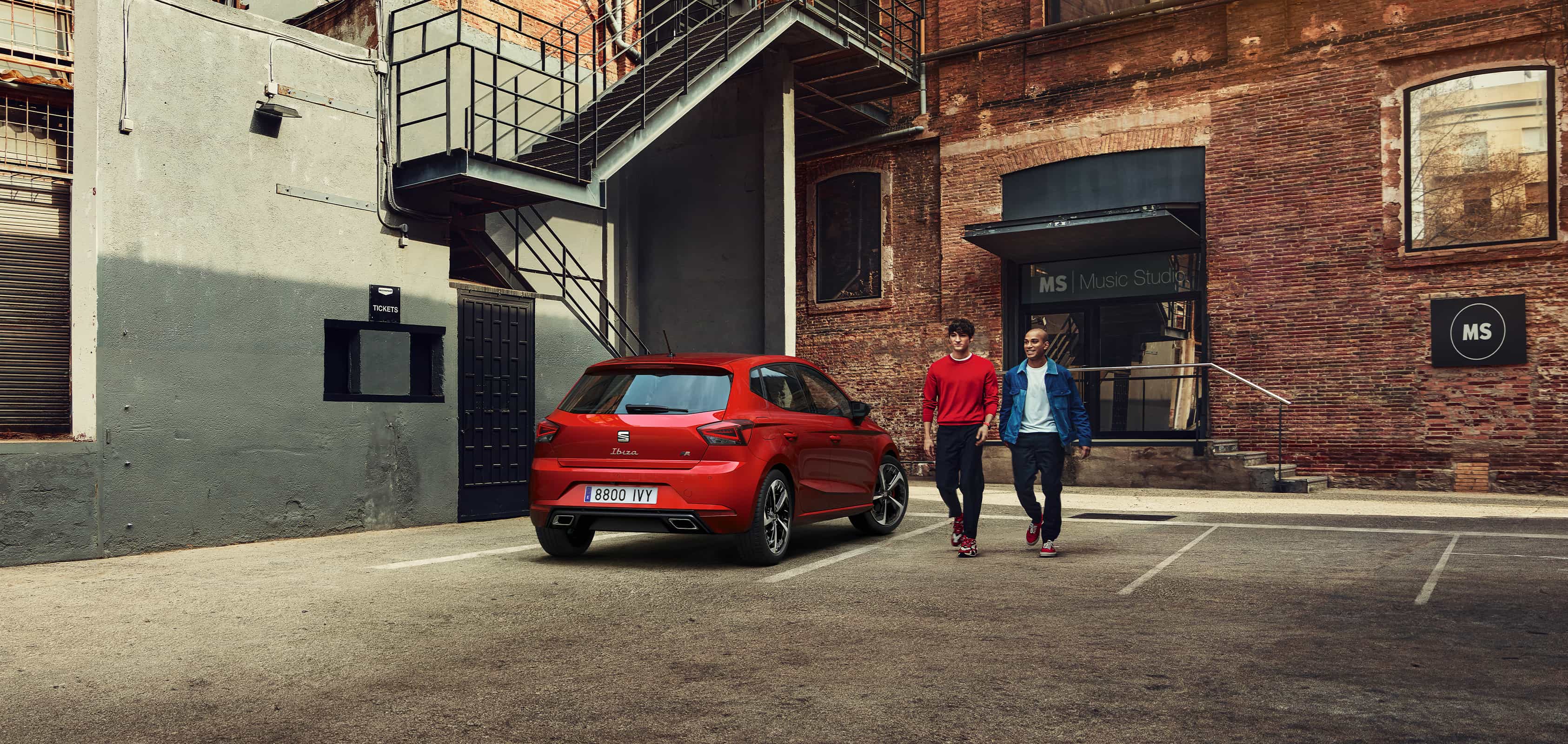 Two men walking next to SEAT Ibiza desire red colour