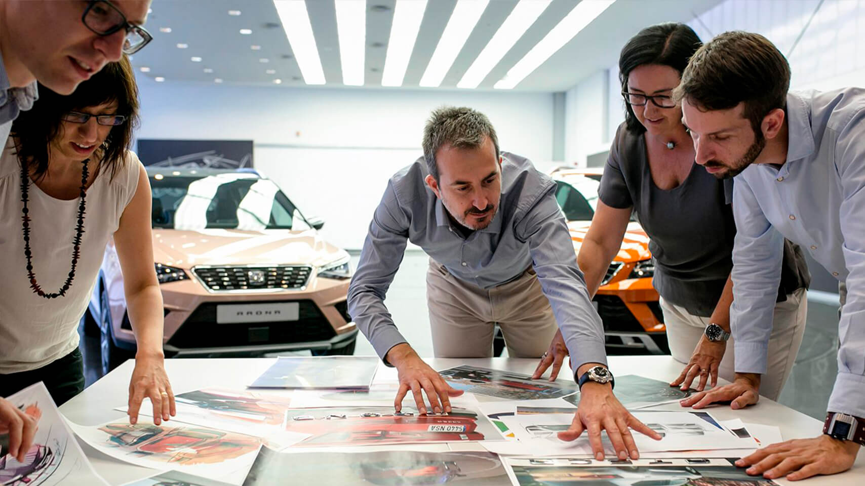 Workers from SEAT observing pictures with SEAT Ibiza and SEAT Arona behind 