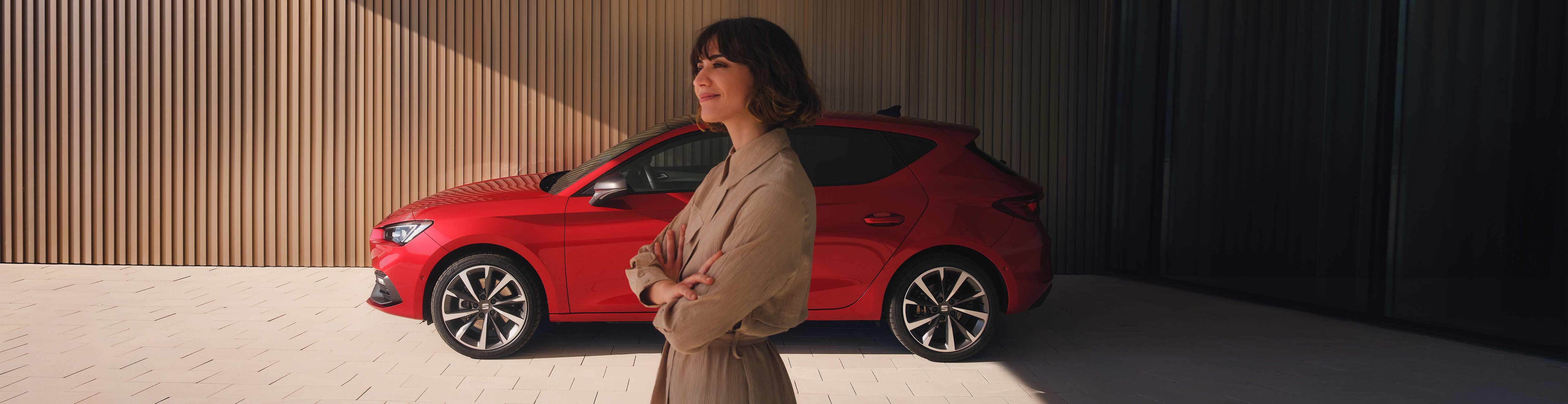 Woman standing close to SEAT Leon 5D desire red colour