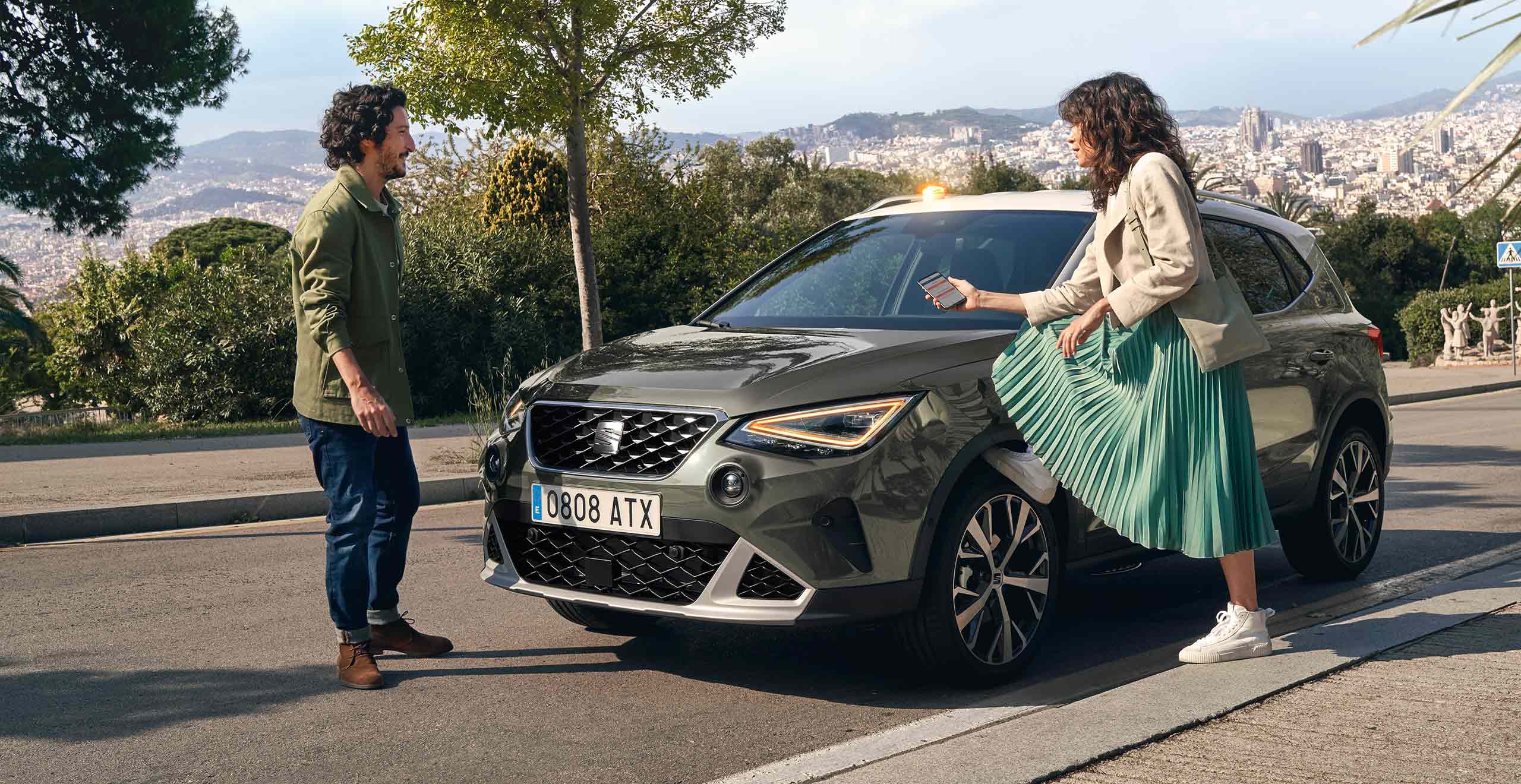 Woman with her foot on SEAT Arona´s wheel looking at her smartphone