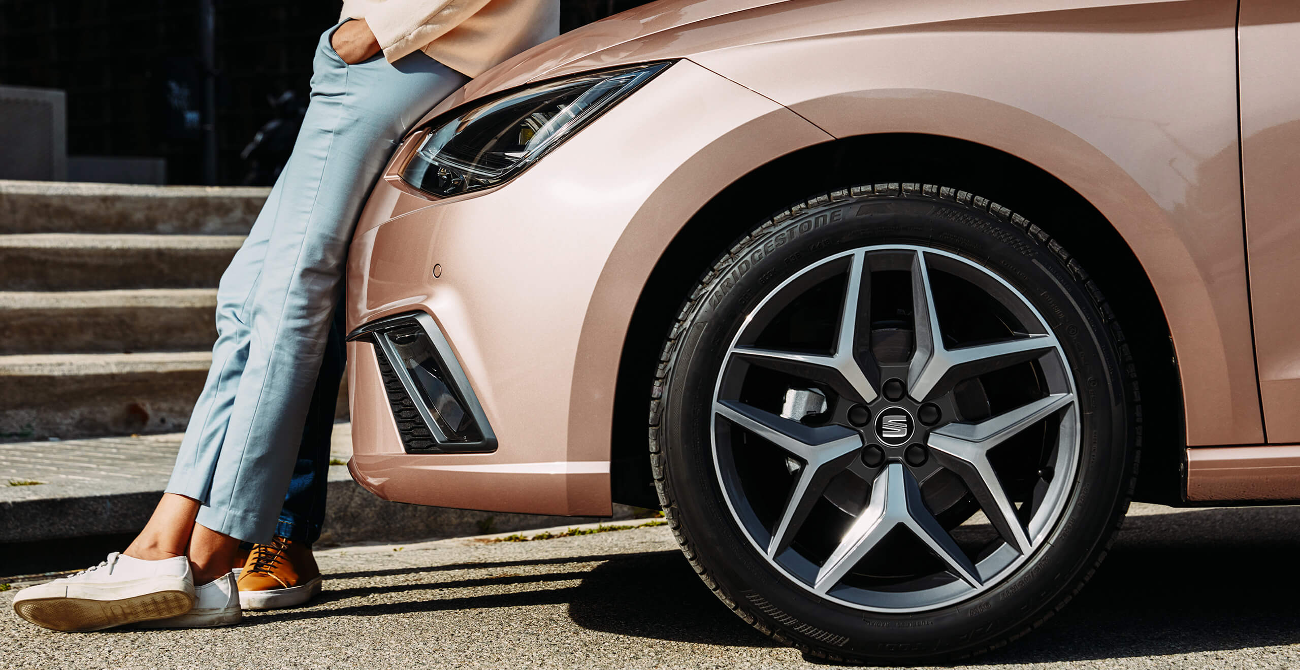 Servizi e manutenzione per vetture nuove SEAT, controlli per revisione auto – donna appoggiata a una vettura SEAT oro rosato