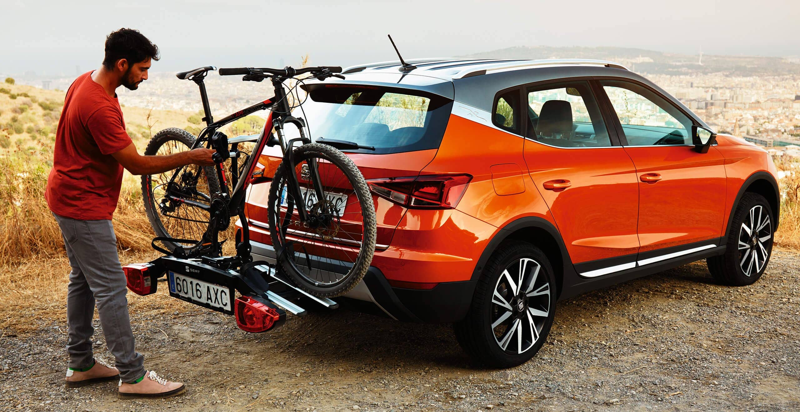 Servizi e manutenzione per vetture nuove SEAT – un uomo sistema una bicicletta su un portabiciclette sul retro di un crossover SEAT Arona