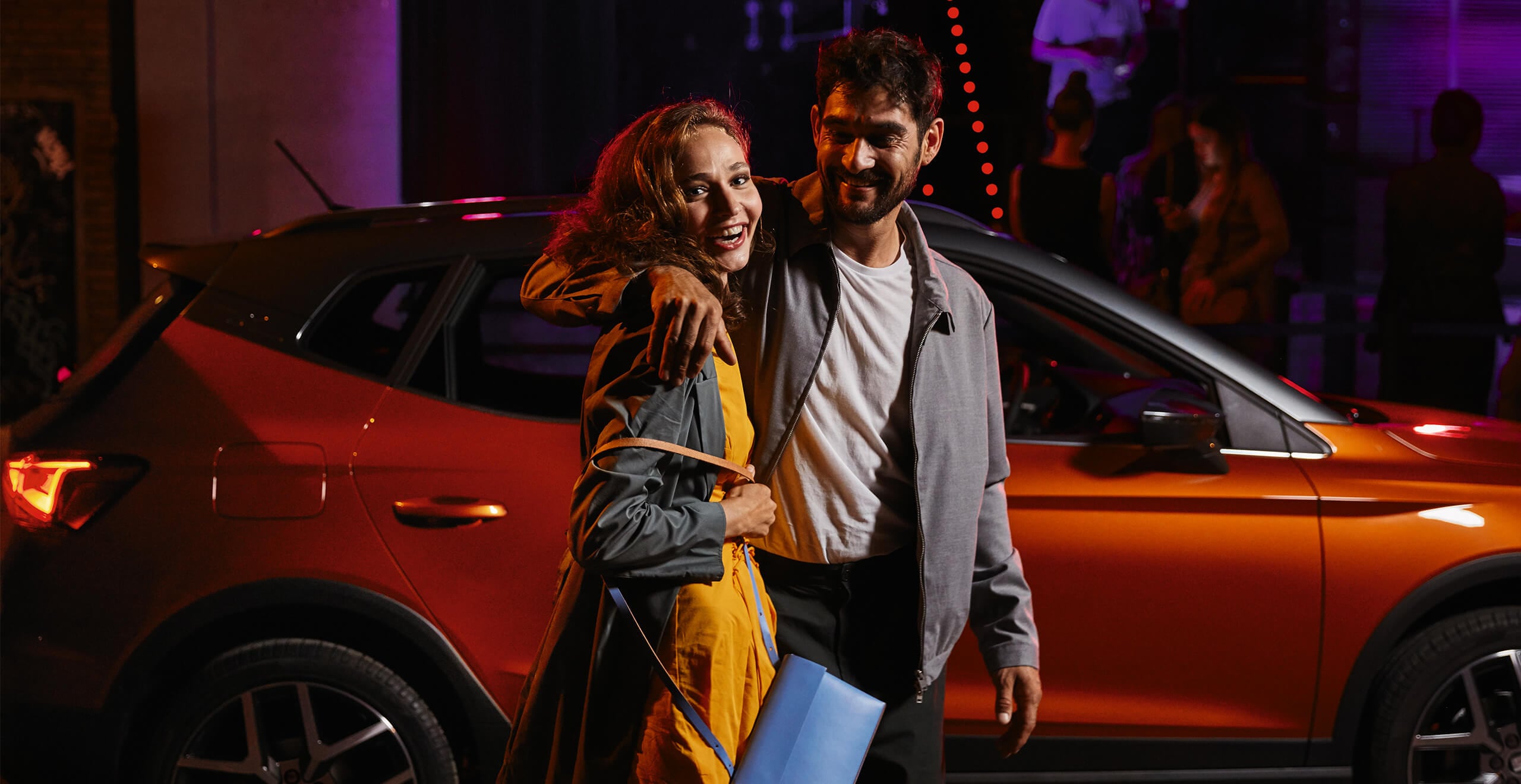 Servizi e manutenzione SEAT – una giovane coppia cammina di notte davanti a un SUV crossover SEAT Arona